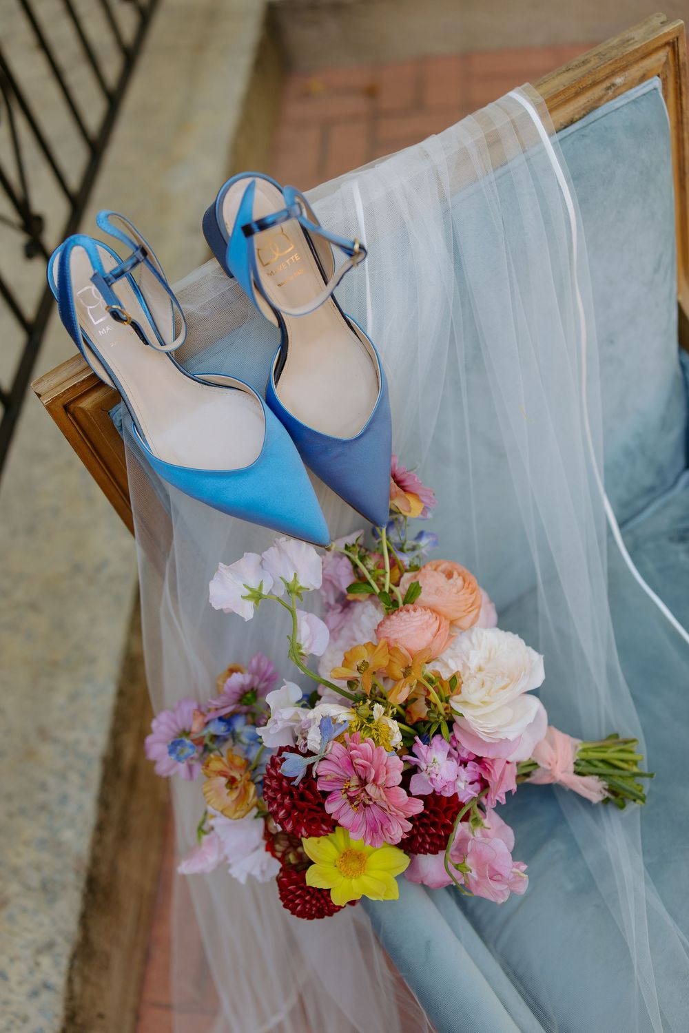 A close-up detail of a light blue tulle fabric with delicate pink and yellow floral arrangements.