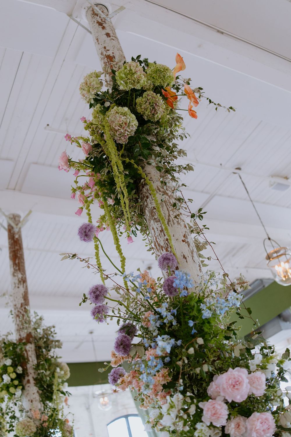 Lush floral wedding decorations, white ceiling with pink roses and mixed wildflowers creating romantic ambiance.