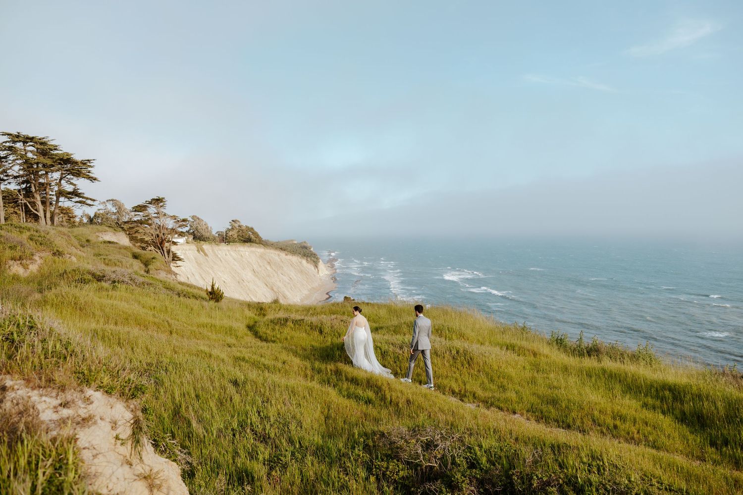 bride and groom embracing each other with the golden gate bridge and san francisco behind them during sunset on their elopement day