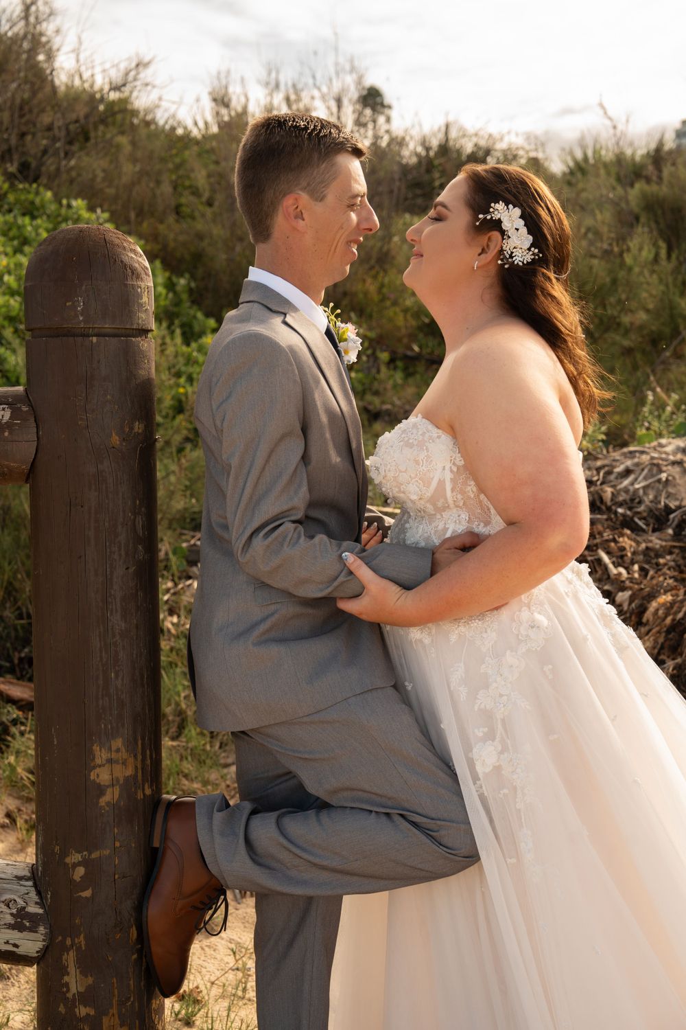 Wedding photography of bride and groom on Wollongong beach smiling.