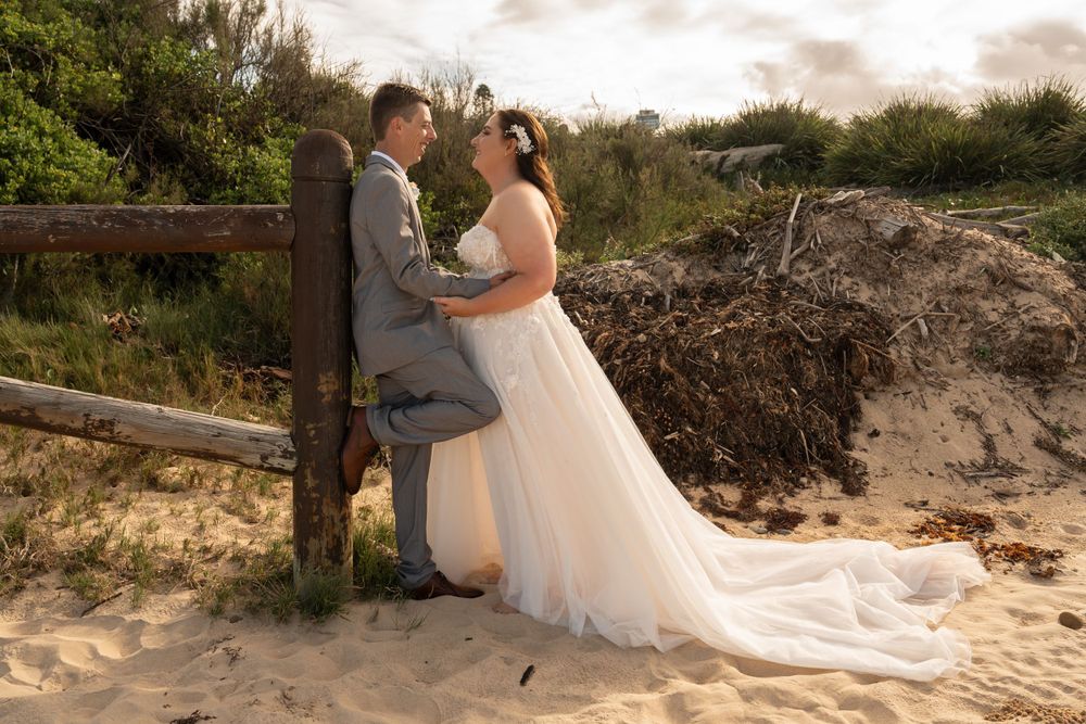 Newly married couple on Wollongong beach holding hands.