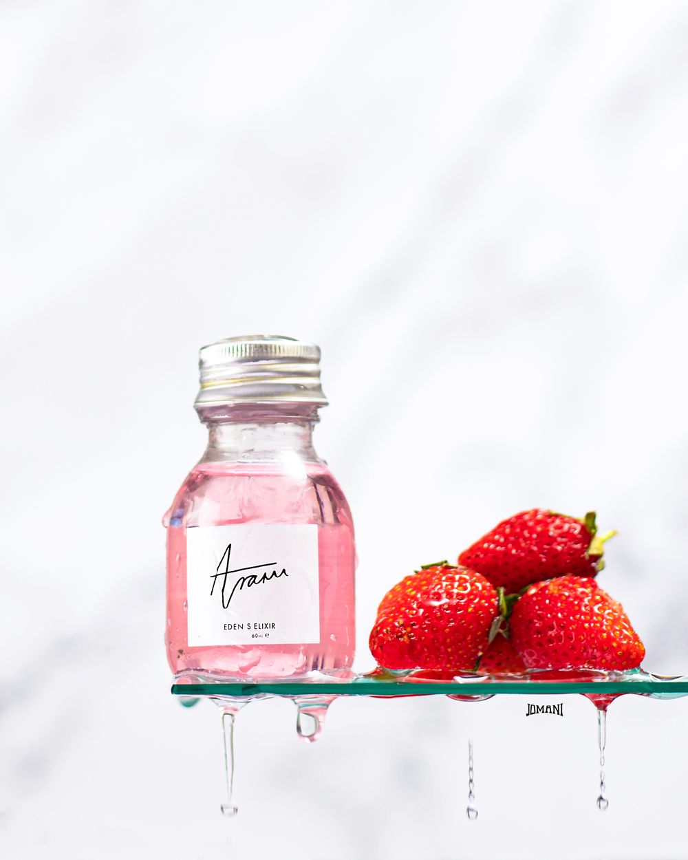 Pink strawberry elixir bottle by Amari displayed on glass shelf with fresh strawberries on marble background.
