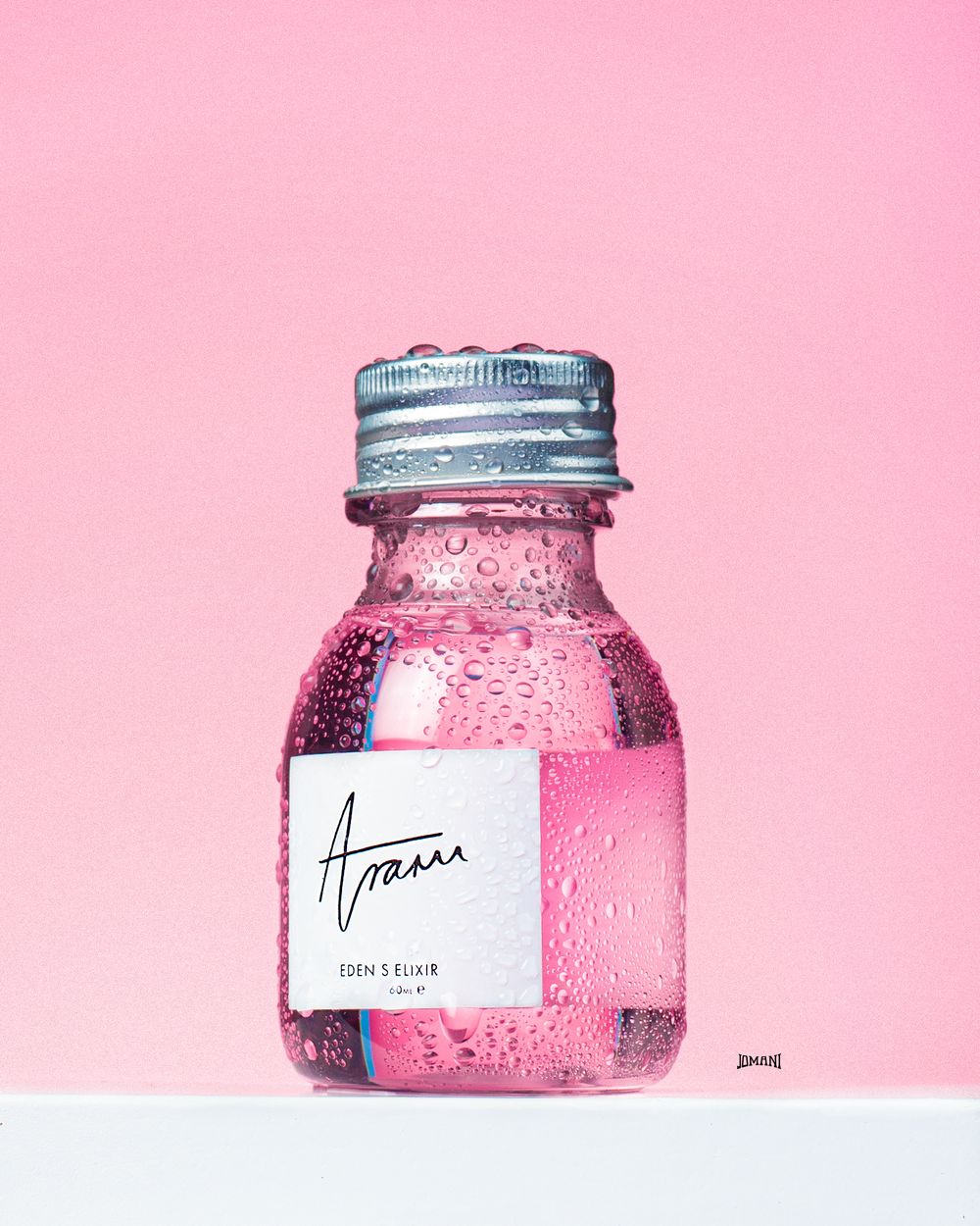 Aram Eden's Elixir pink liquid in small glass bottle with silver cap on pink background.