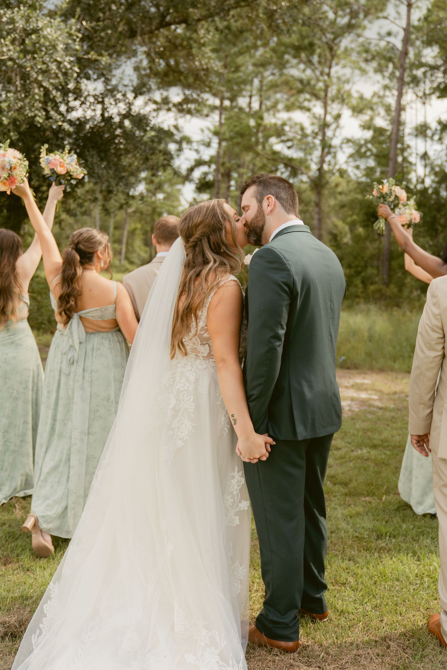 Wedding party celebrating with joyful poses in outdoor garden setting.