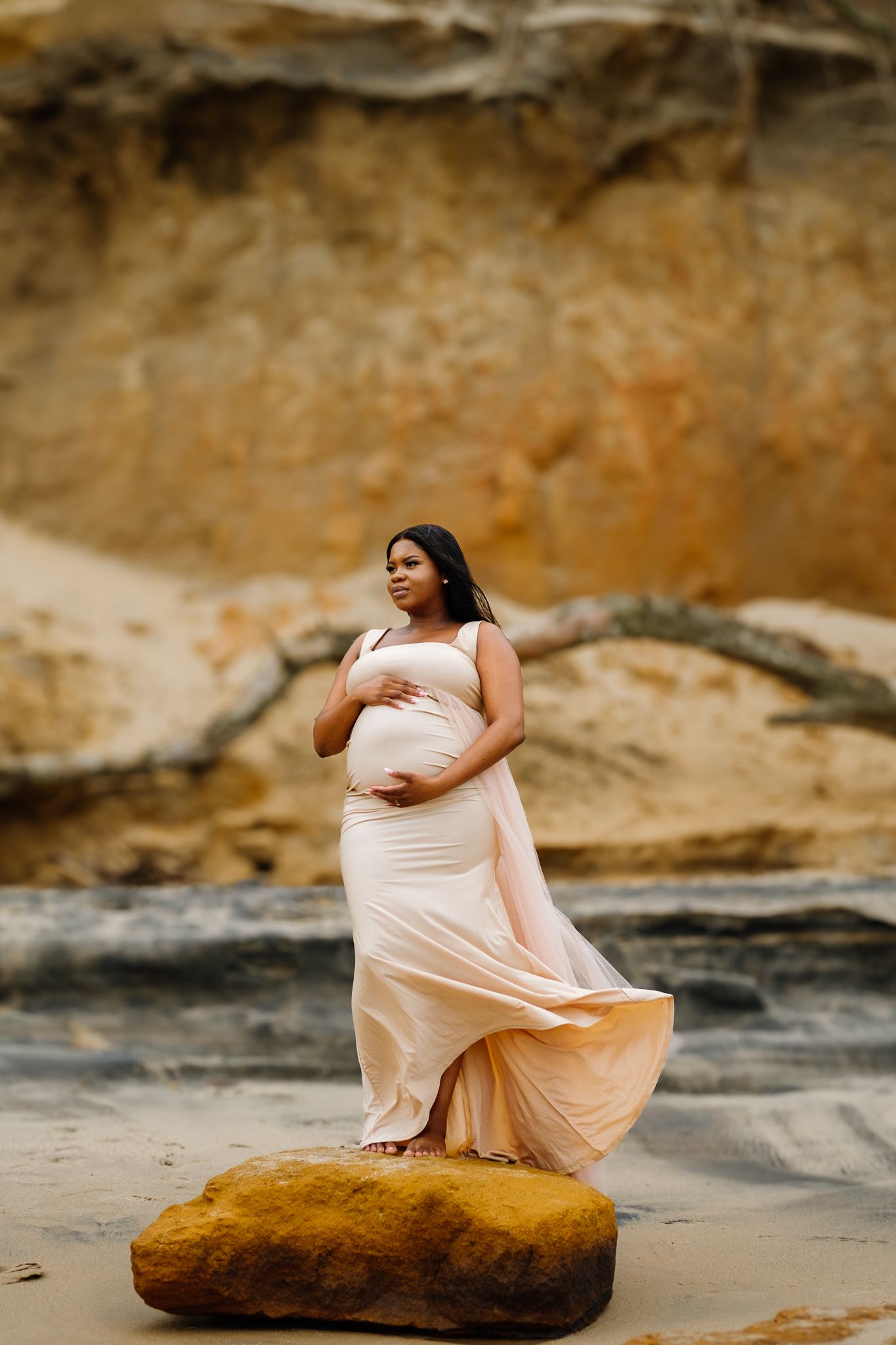 Maternity portrait of a woman standing on a rock in a natural outdoor setting