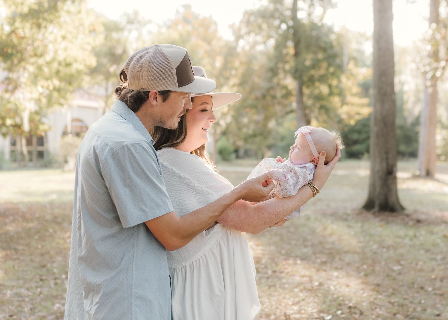 Family in coordinated earth-tone outfits walking together through a lush green meadow on a sunny day.