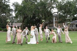 Joyful wedding party celebrates on sprawling lawn with Spanish moss trees.