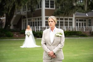 Wedding party poses on manicured lawn in front of southern mansion.
