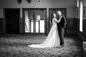 Wedding couple embraces in elegant hotel ballroom with patterned carpet.