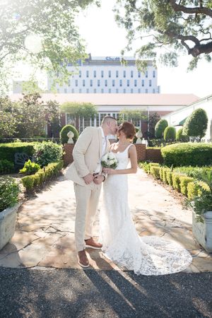 A couple shares a romantic dance moment on a stone pathway in an elegant garden setting.