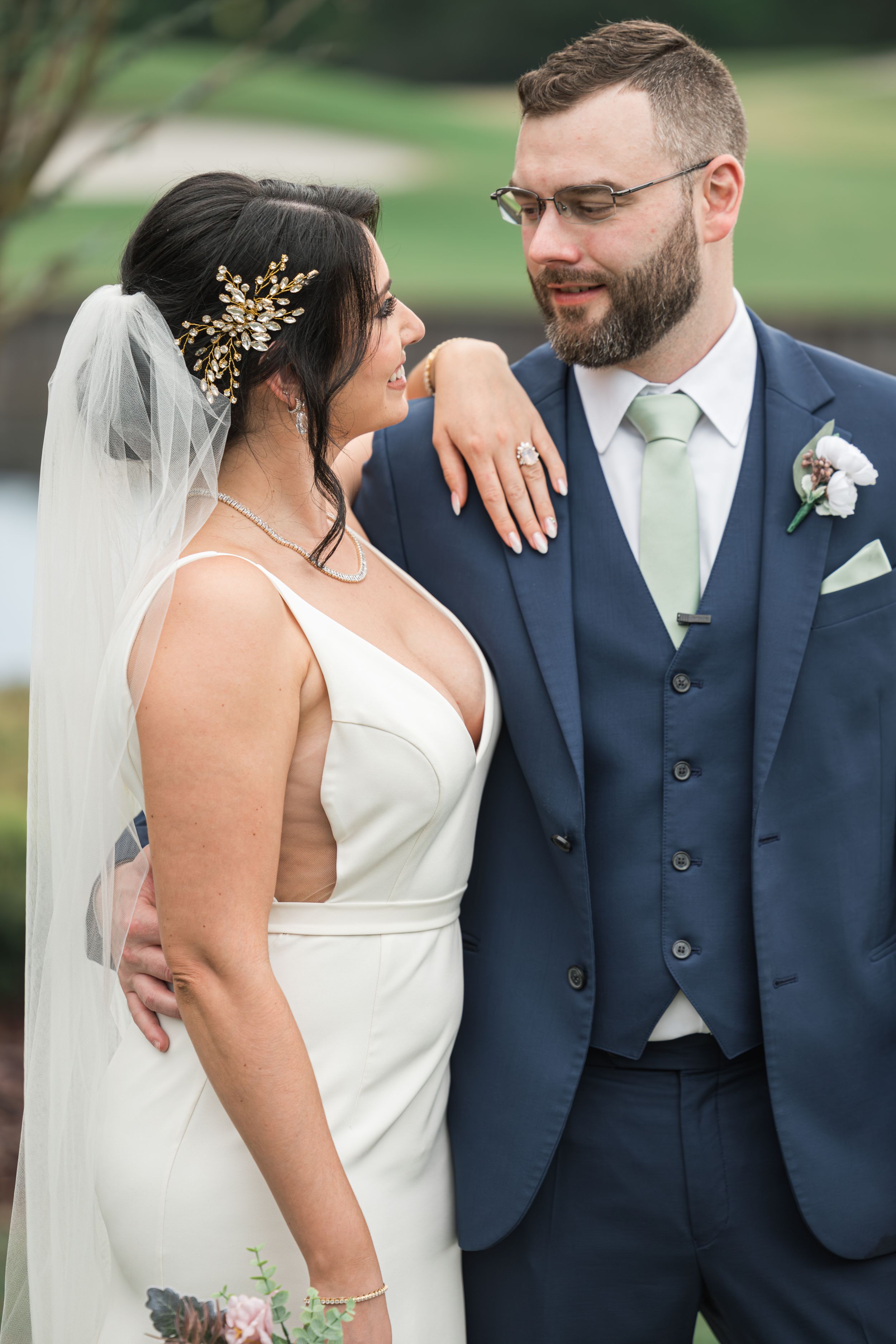 Couple in wedding attire embracing during outdoor portrait session.