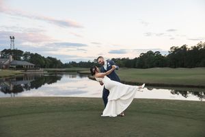 Wedding couple in dramatic poses on golf course at dusk.