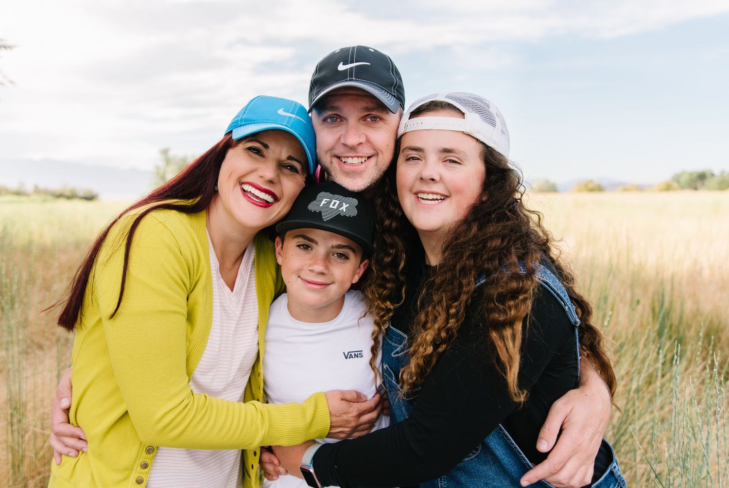 Happy family group hugging and smiling together outdoors in natural setting.