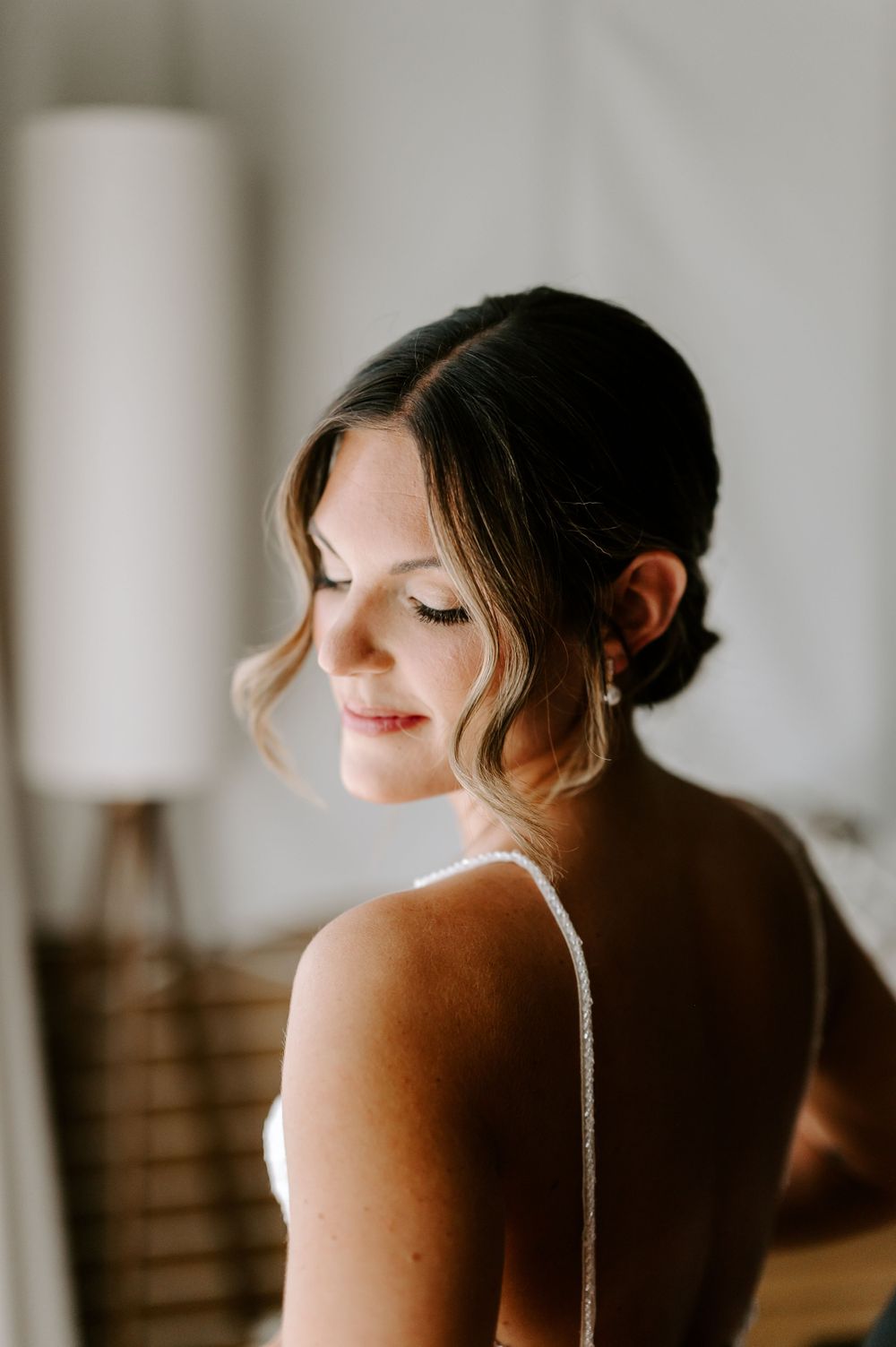 An artistic bridal portrait showing elegant hair styling and dress strap detail.
