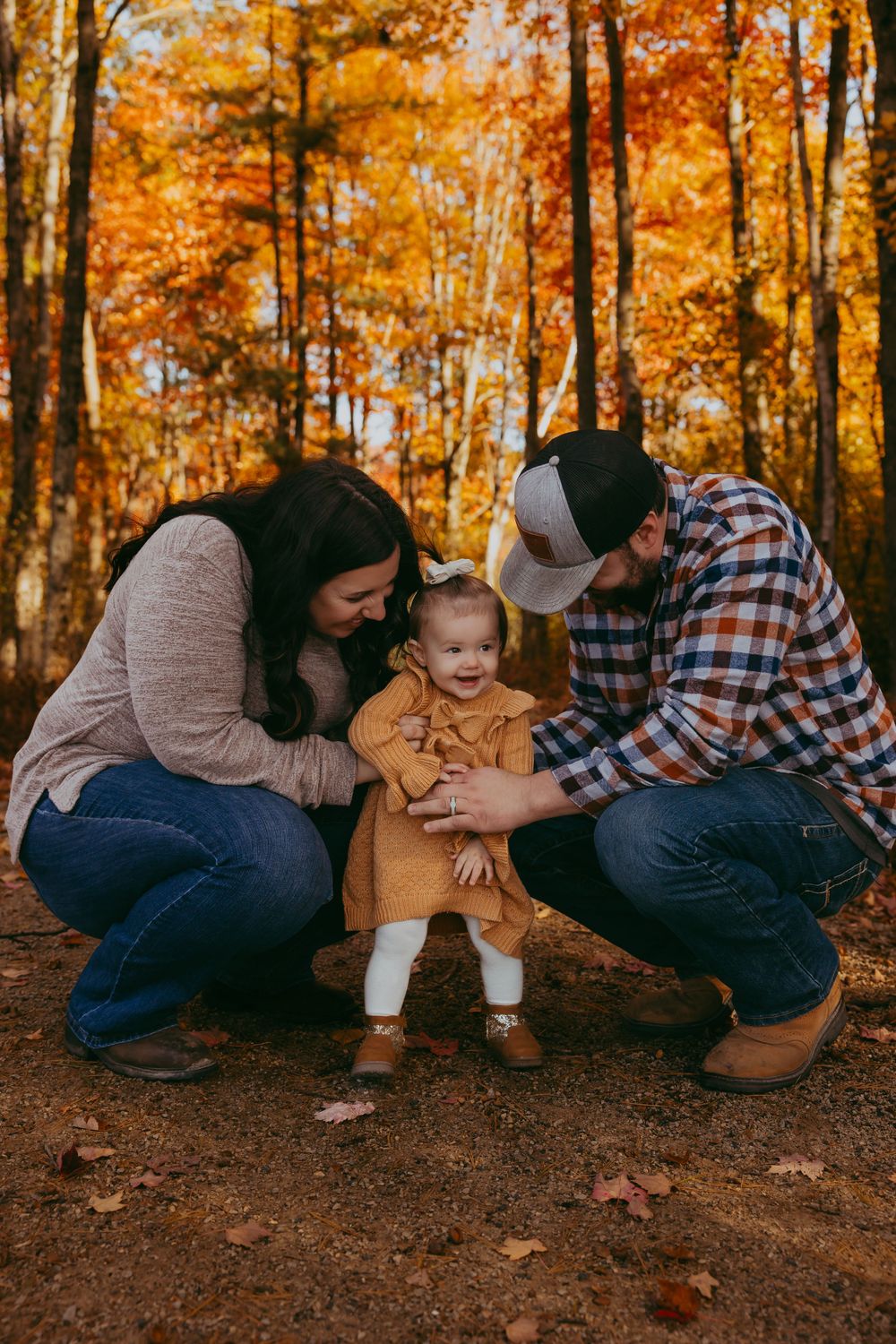 Family enjoying a fall day together in a forest with vibrant orange autumn foliage in the background.