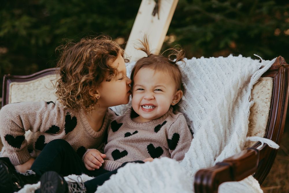 A heartwarming moment captured on a vintage chair with a white blanket as two share a sweet interaction together.