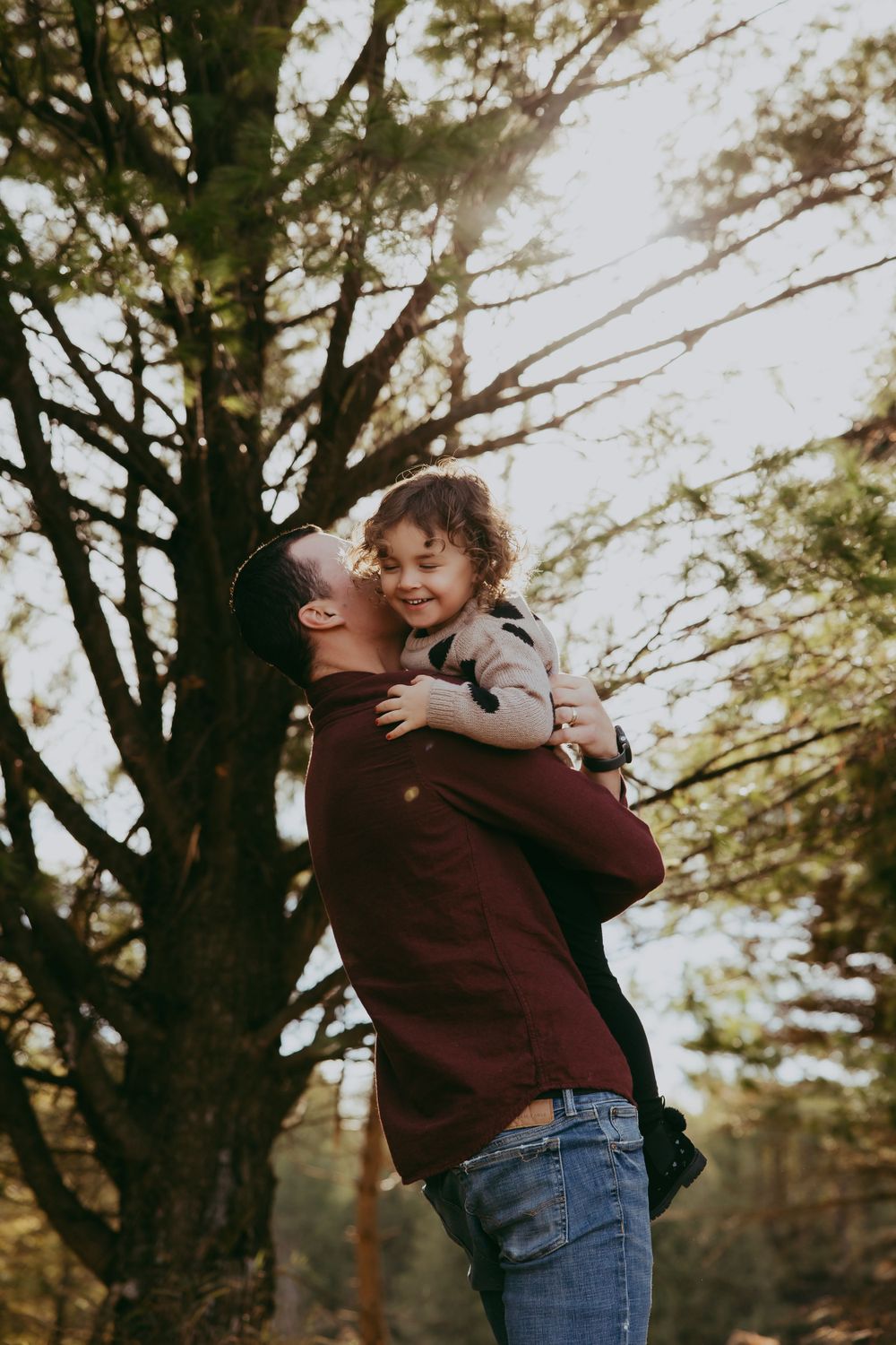 A joyful moment captured in autumn as a child rides piggyback through the woods during golden hour.