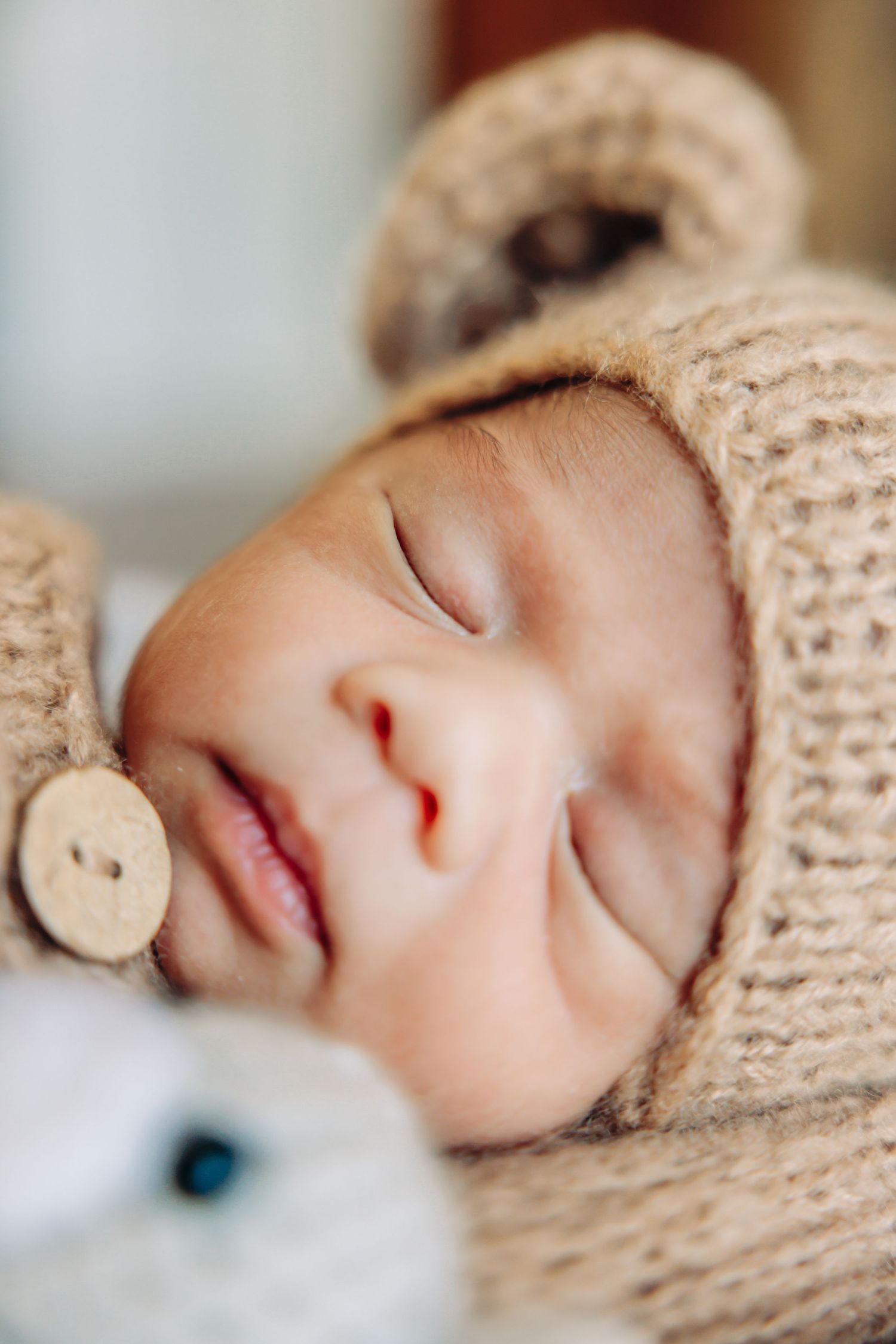 Close up of sleeping infant wearing cozy knit hat with wooden button detail.