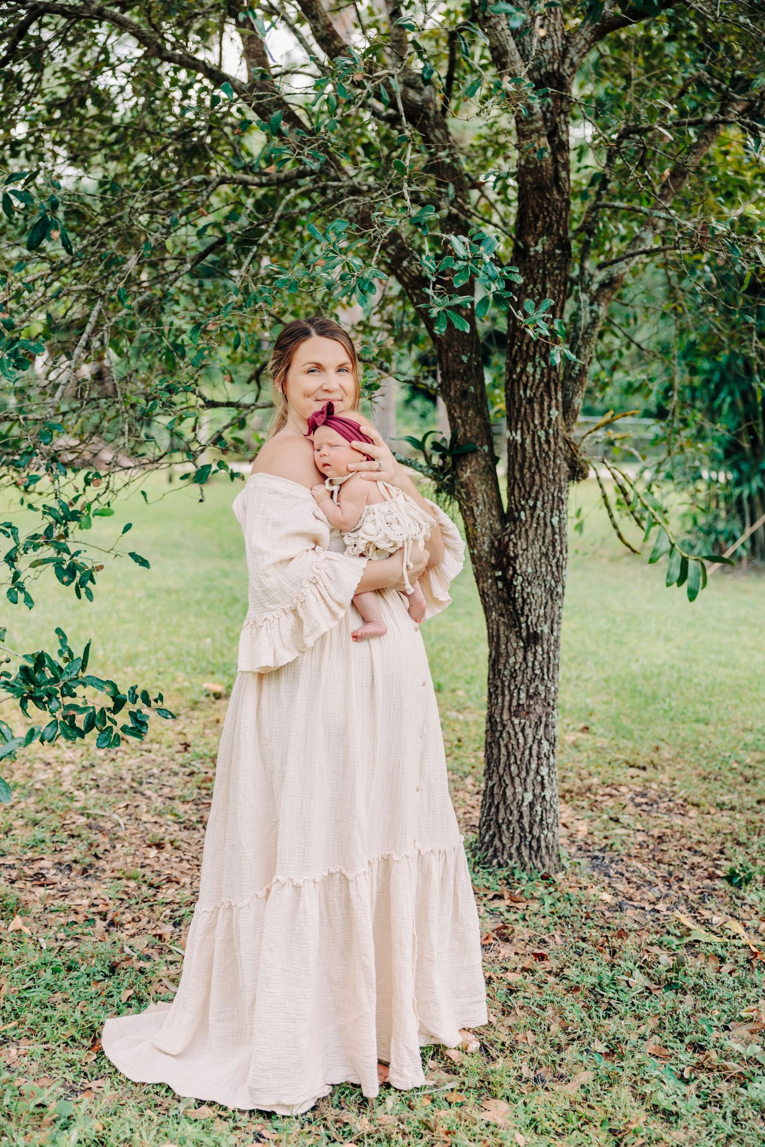 Family portrait under a tree in an outdoor setting with flowing cream dress.