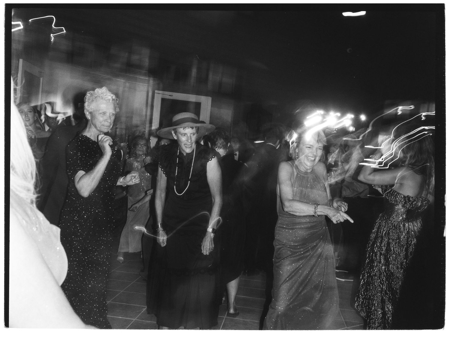 Dark reception venue filled with dancing wedding guests illuminated by party lights.
Film, Authentic, Cinematic photographer, Film Photo