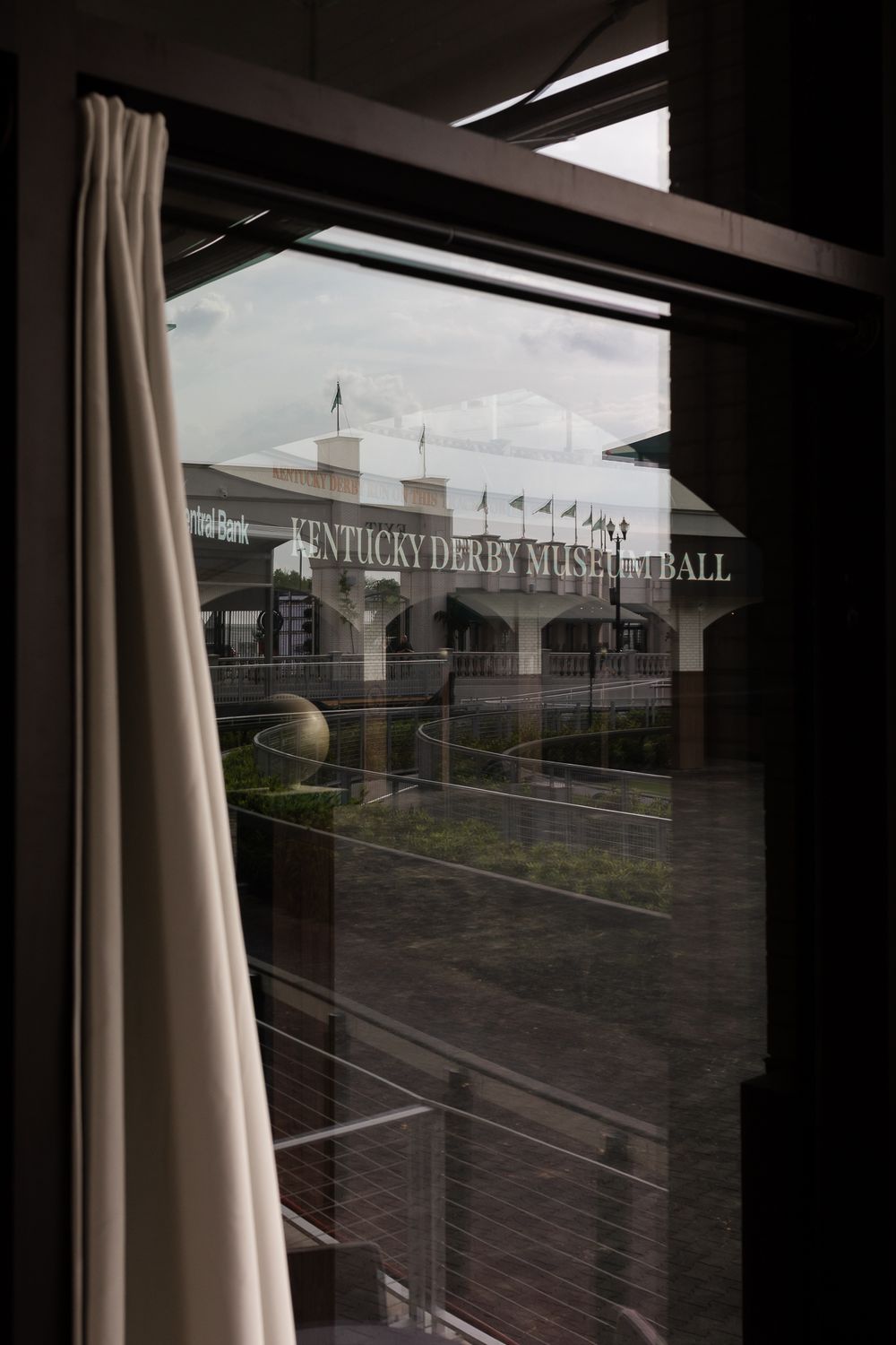 View through a window of the Kentucky Derby Museum Hall building exterior with flags and courtyard.