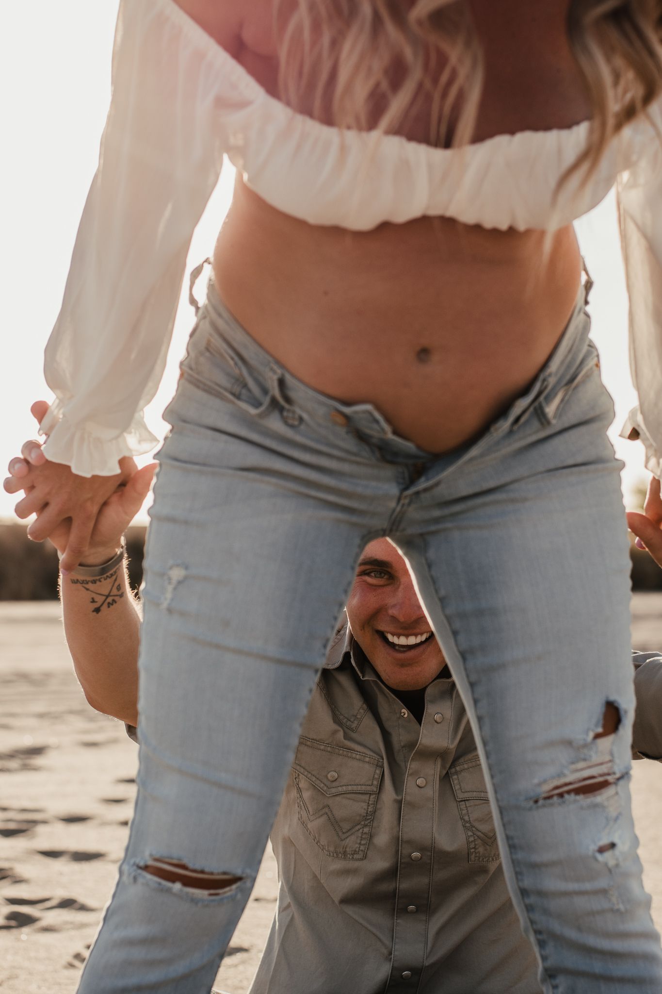 A playful intimate moment captured between a couple wearing casual clothing outdoors.