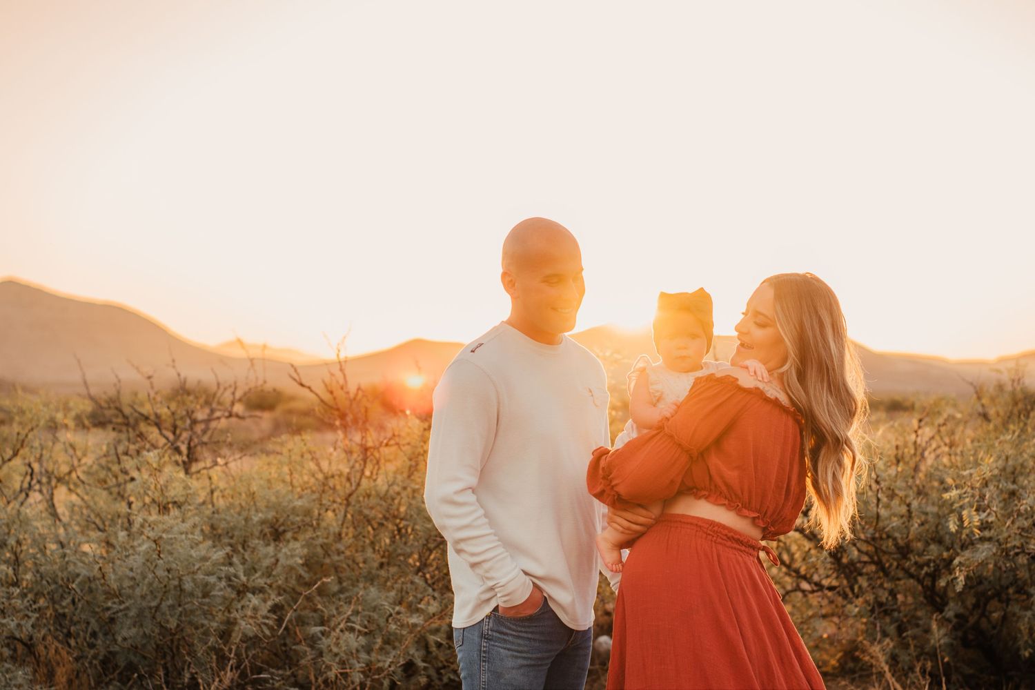 A couple standing together at sunset in a desert landscape with warm golden lighting.