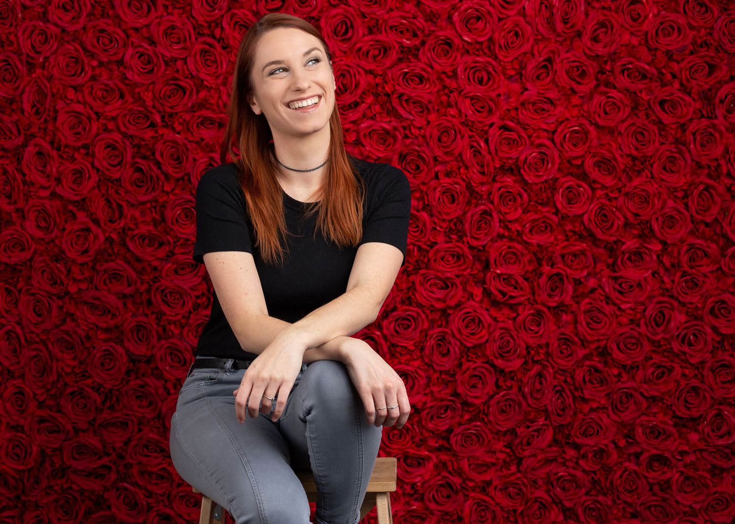 Portrait series against red rose backdrop wearing casual attire.