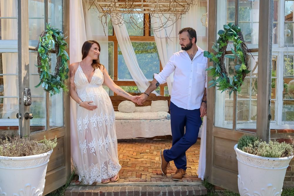 Romantic couple photoshoot in a bright sunroom with white decor and potted plants.