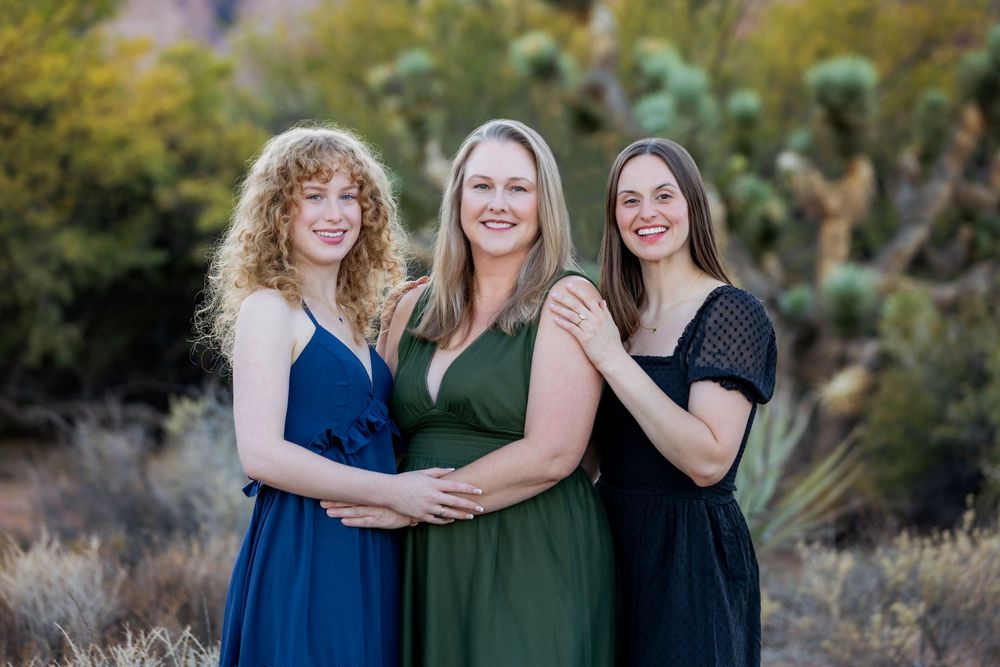 A group poses together outdoors in coordinating blue and green outfits during a photo session at sunset.