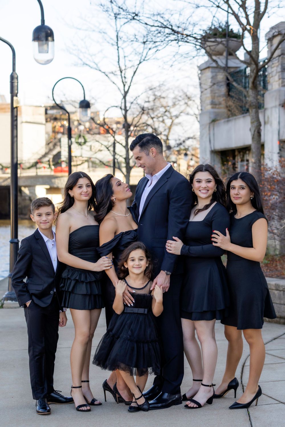 Wedding party in black formal attire poses playfully in a series of candid outdoor photos.