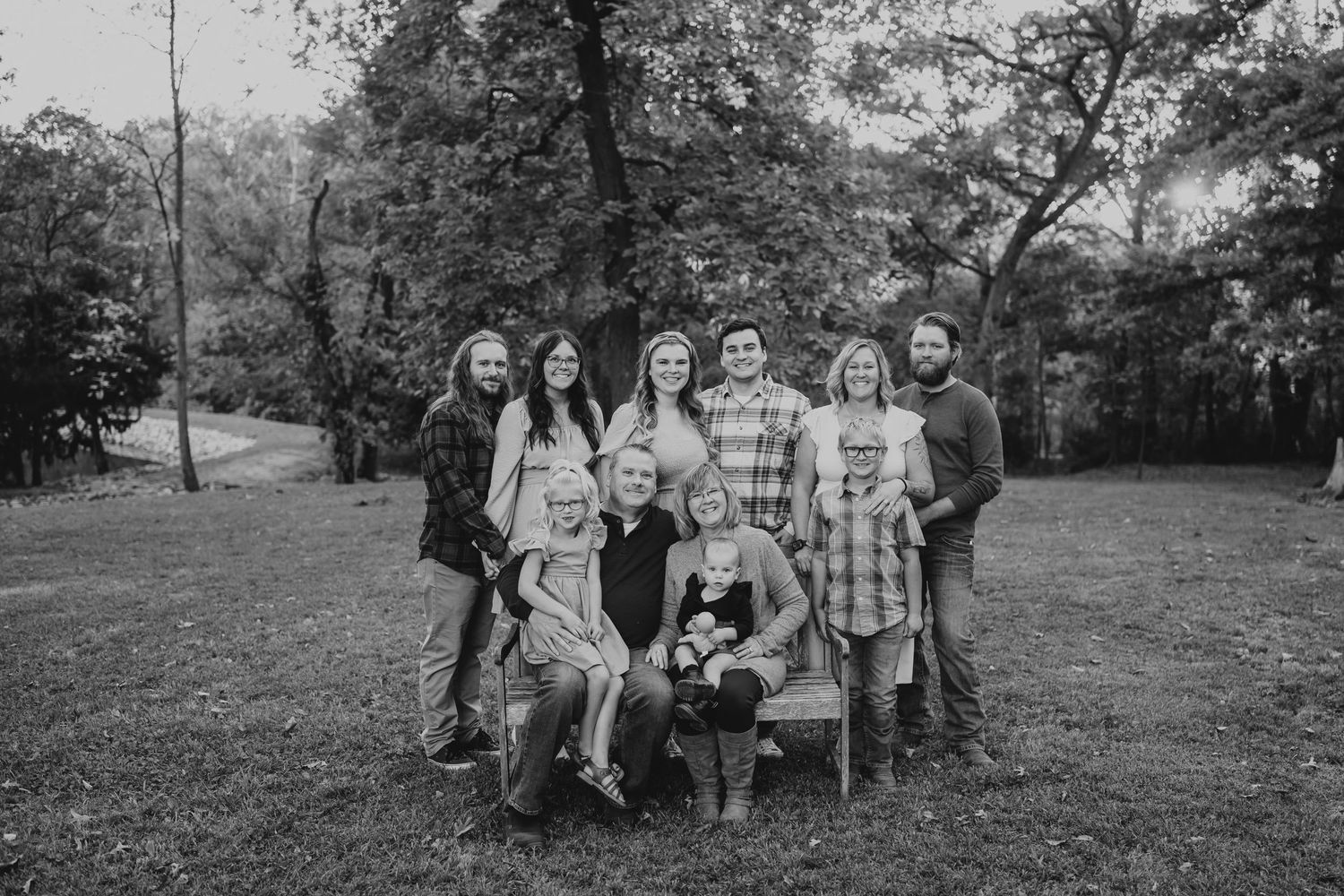 A happy family photo in black and white. They are sitting in a park smiling together.