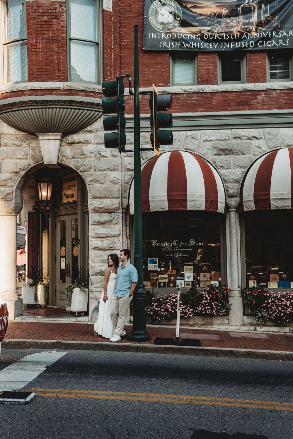 Historic storefront with red and white striped awnings and stone facade on a city street with vintage lamp post.