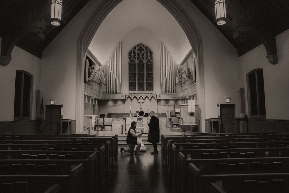 Interior view of a traditional church sanctuary with wooden pews, arched ceilings, and gothic architectural details.