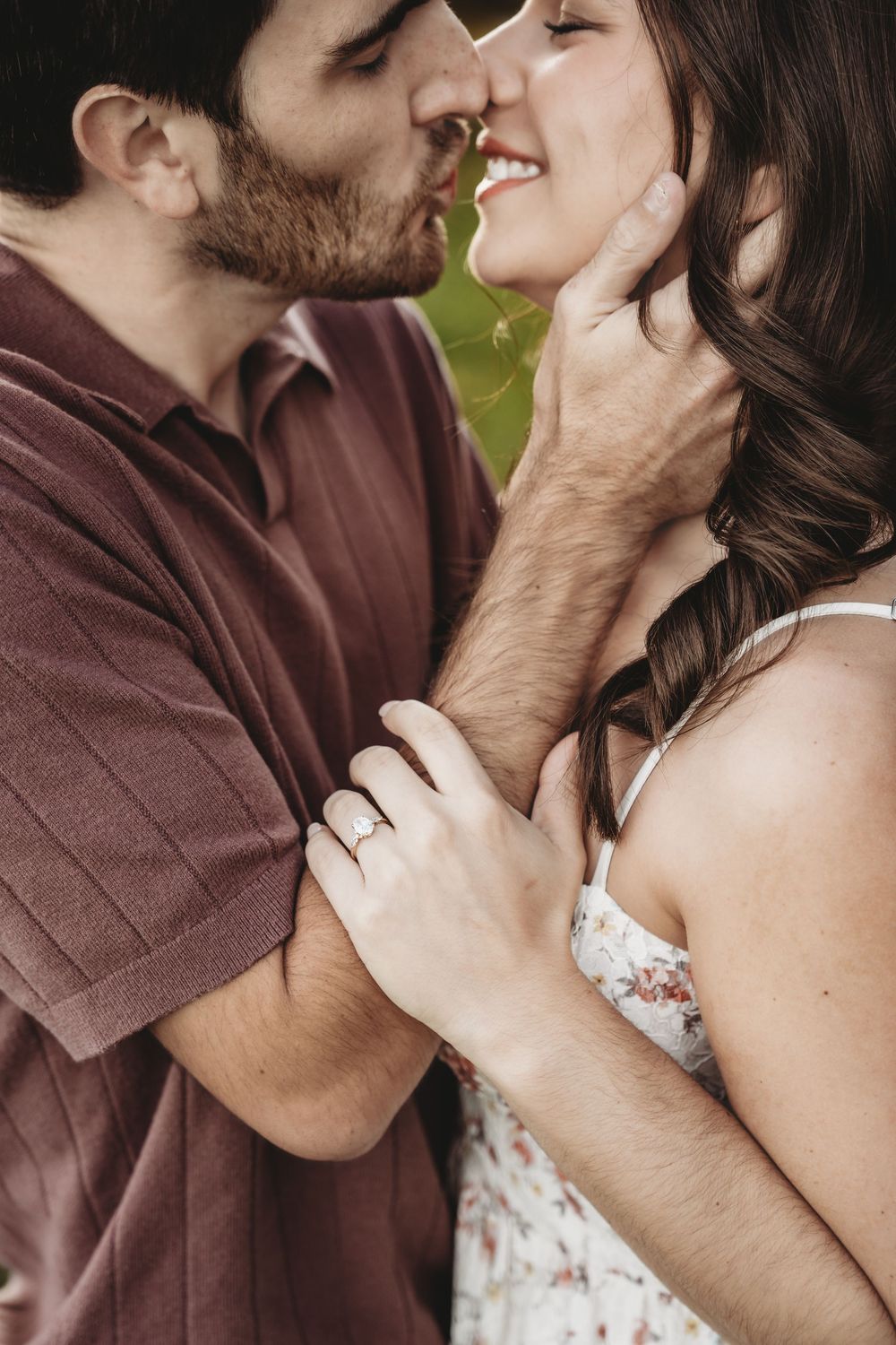 A romantic couple sharing an intimate kiss while wearing brown and white attire in an outdoor setting.