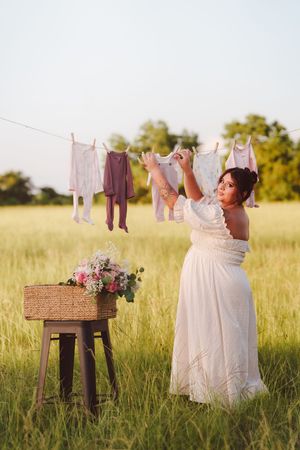 Rustic laundry scene with clothing hanging on line in golden sunlit meadow with antique wooden table.