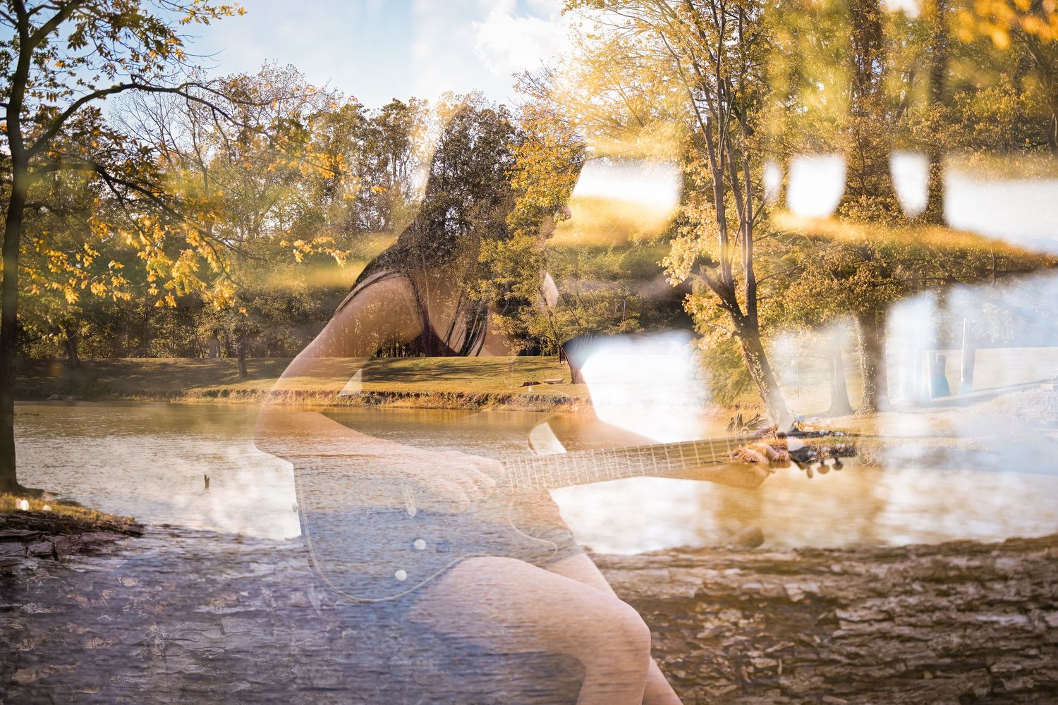 A person in a flowing dress stands in shallow water at sunset creating ripples and reflections in the golden light.
