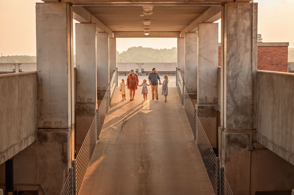 Group of people walking through concrete tunnel during golden hour casting long shadows.