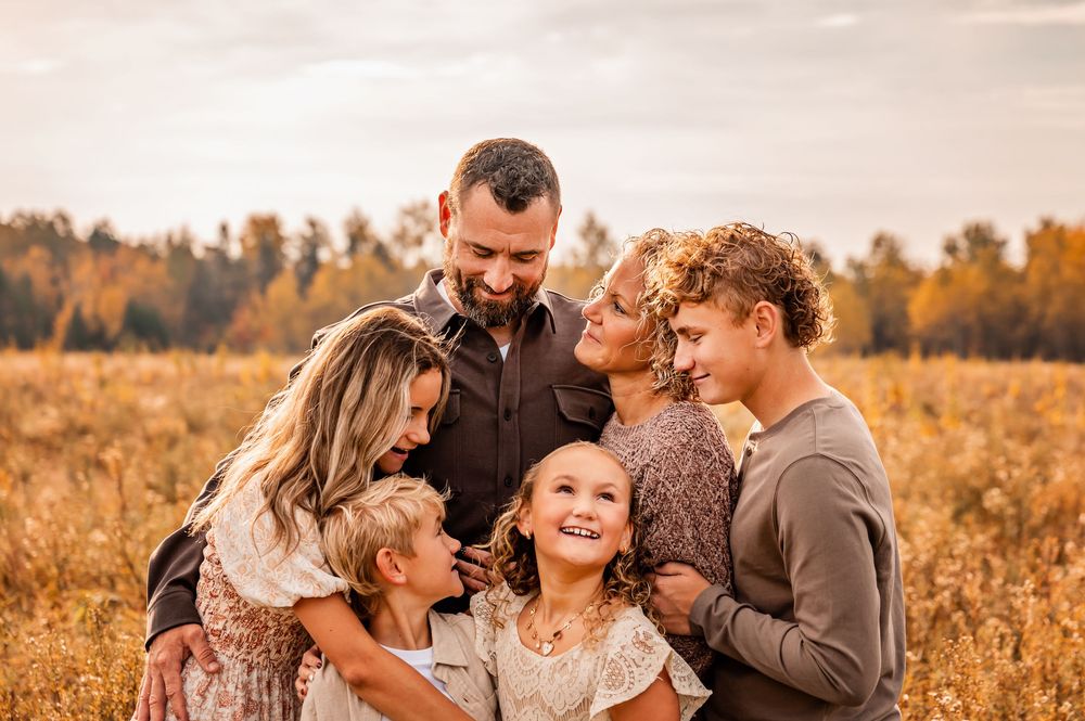 A family shares tender moments together in a golden autumn field during sunset.