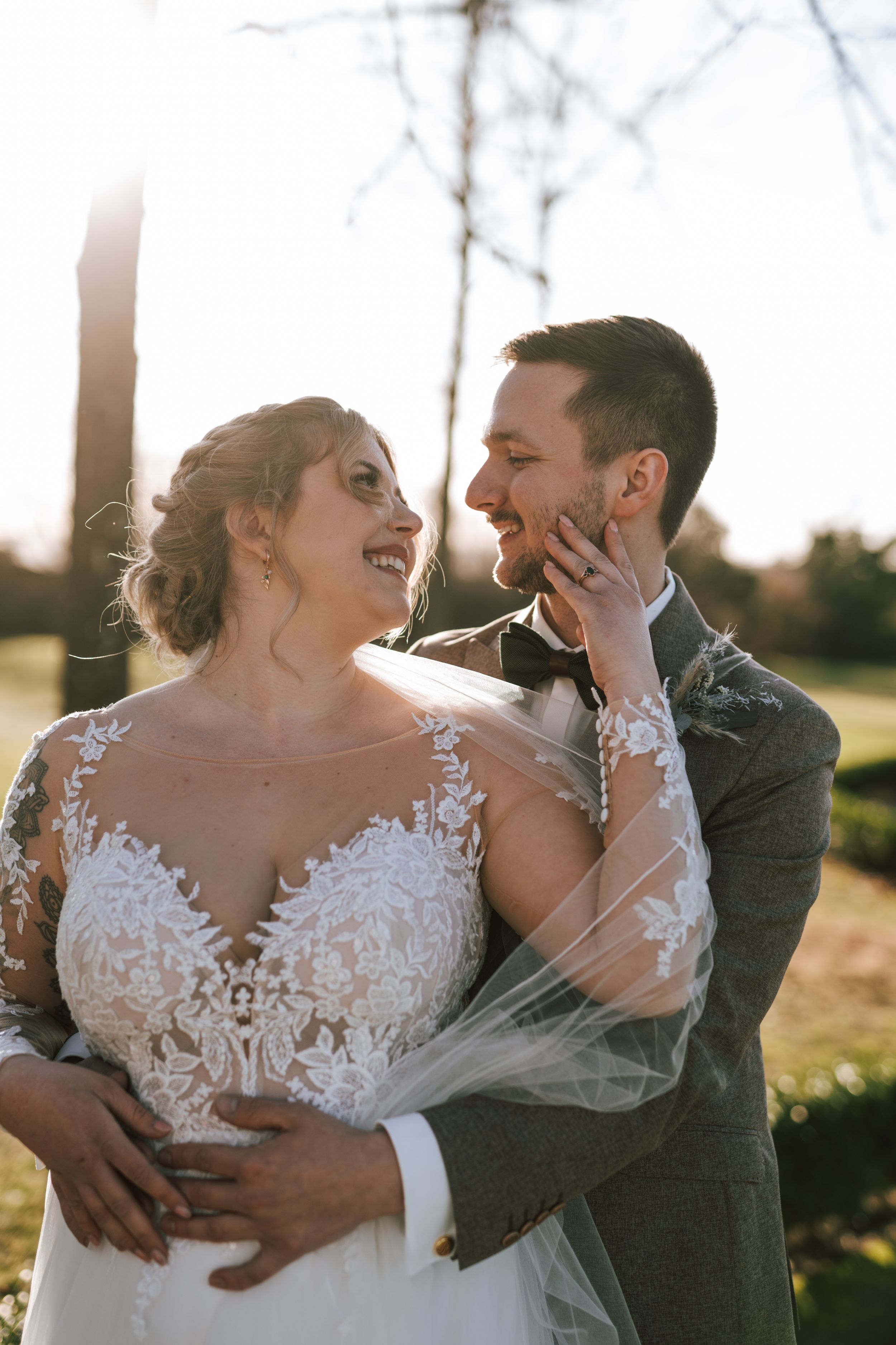 Joyful wedding couple sharing laughter and embraces in outdoor setting.