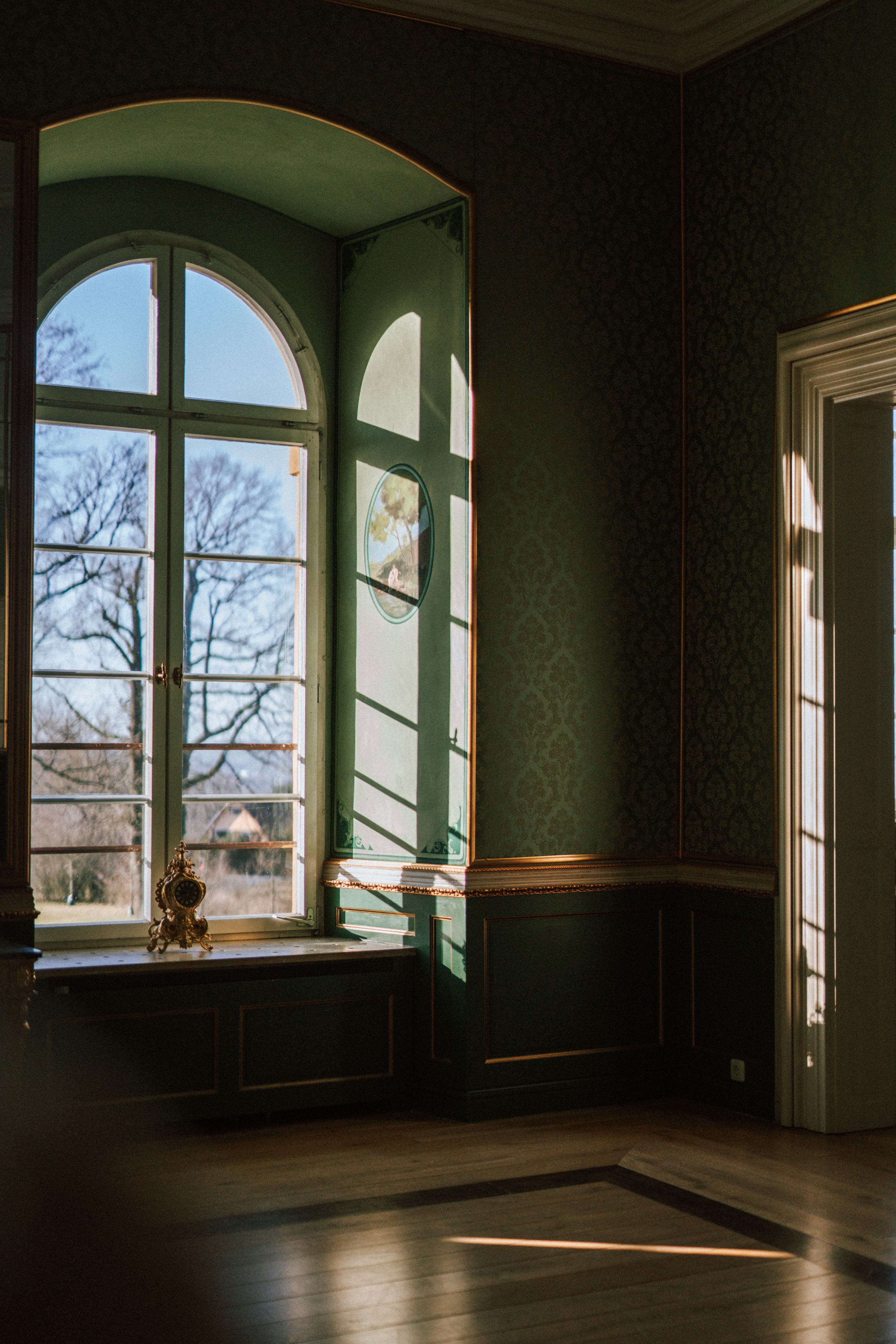 Elegant room with arched windows and hardwood floors bathed in natural light.