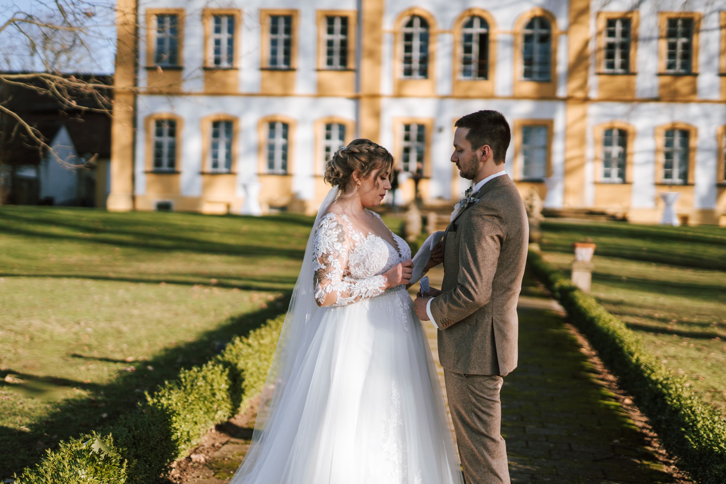 A grand historic building with yellow walls and arched windows serves as an elegant wedding venue backdrop.