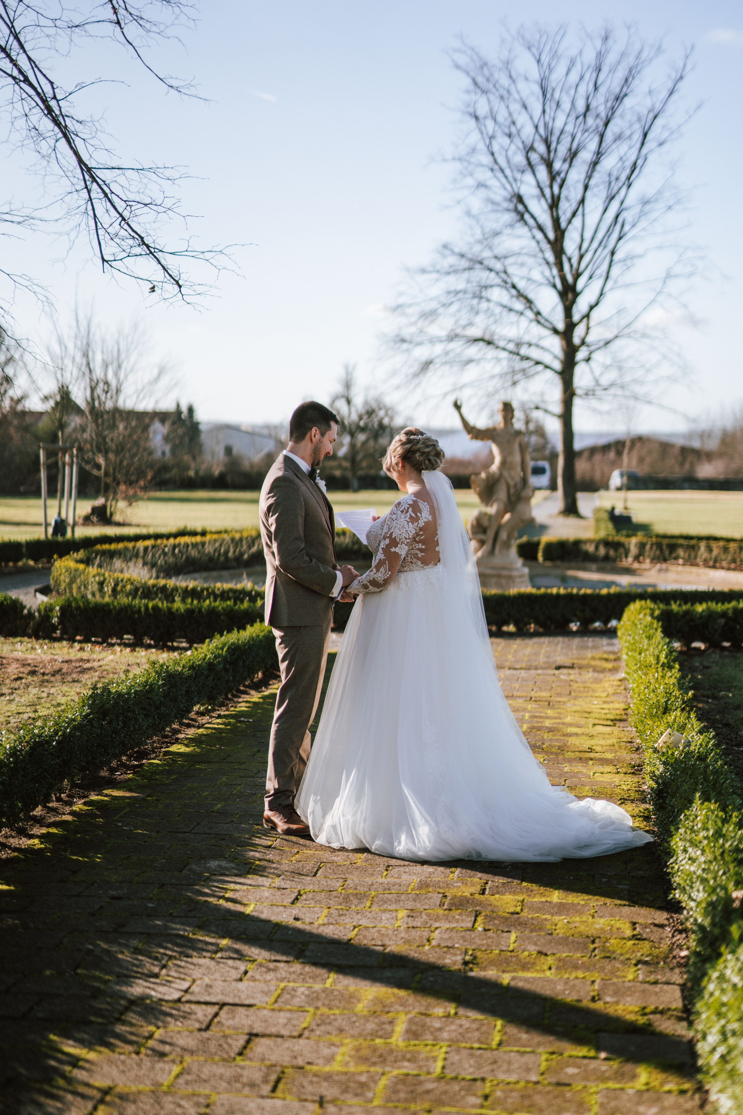 Newlyweds sharing a moment in a garden with stone pathways and winter trees.