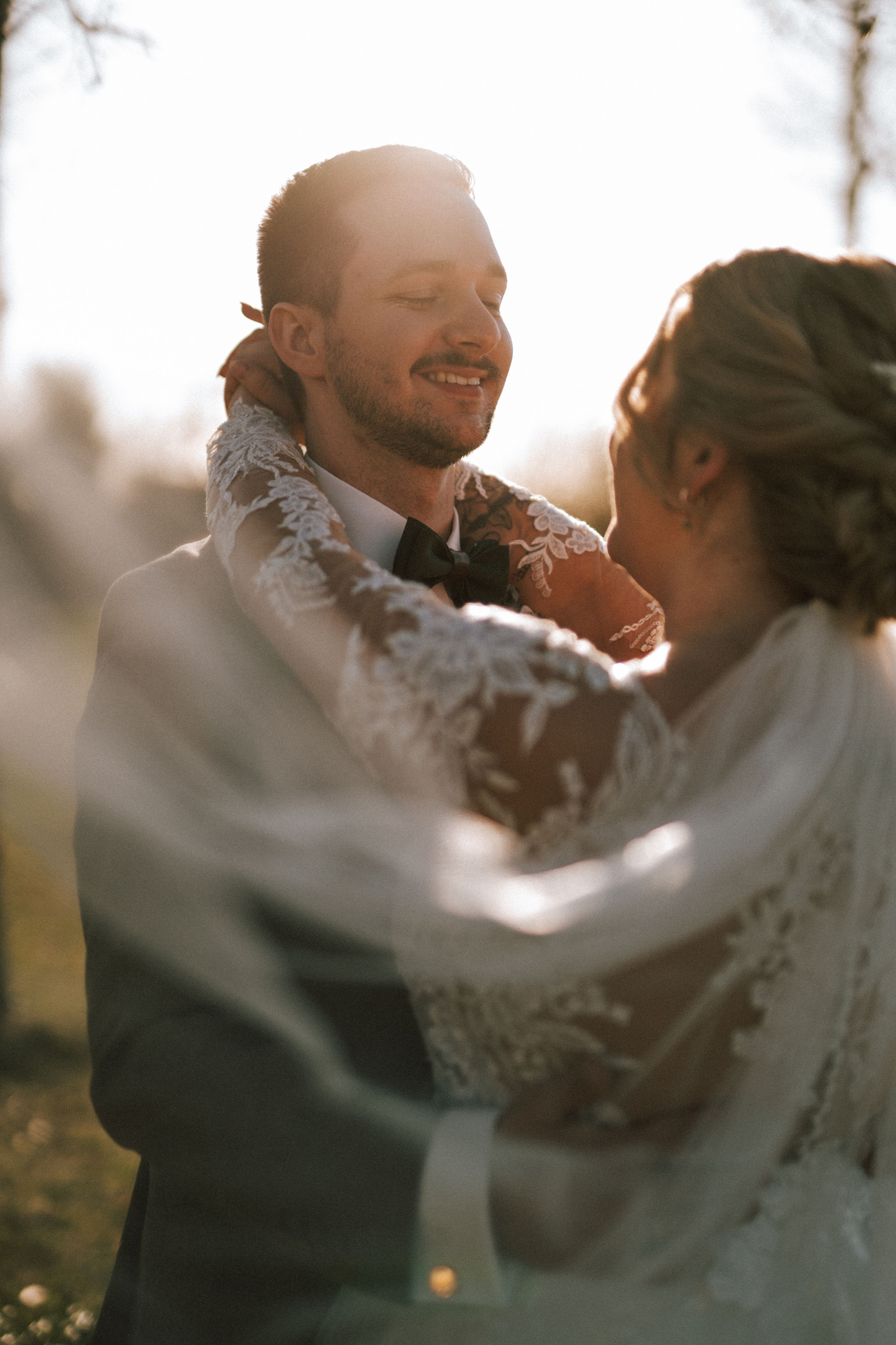 Sunlit wedding couple embracing during golden hour portraits.