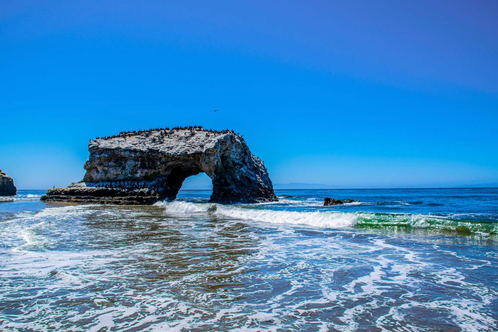 Natural Bridge Rock at Santa Cruz beach with waves crashing against its dramatic stone arch formation.