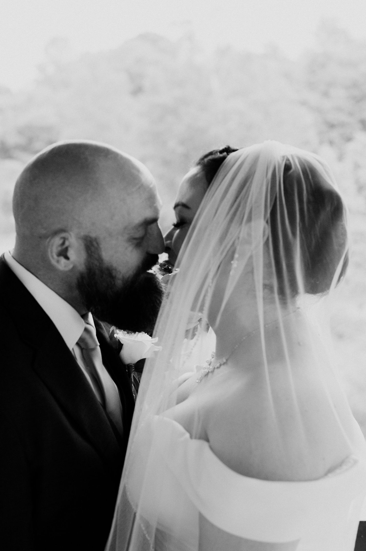 Black and white wedding photo capturing a romantic moment between newlyweds.