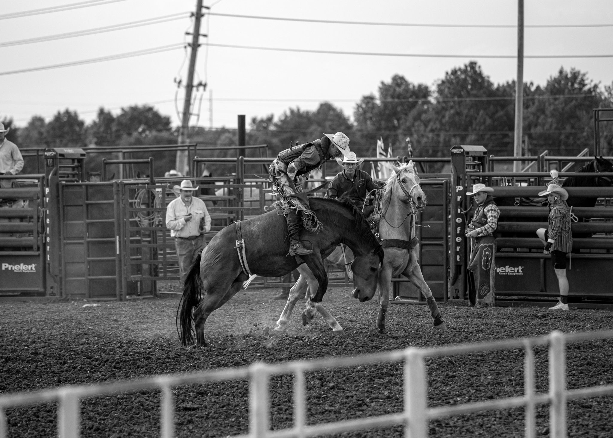 A rodeo competitor rides a bucking horse during a bronc riding event at a rural competition.