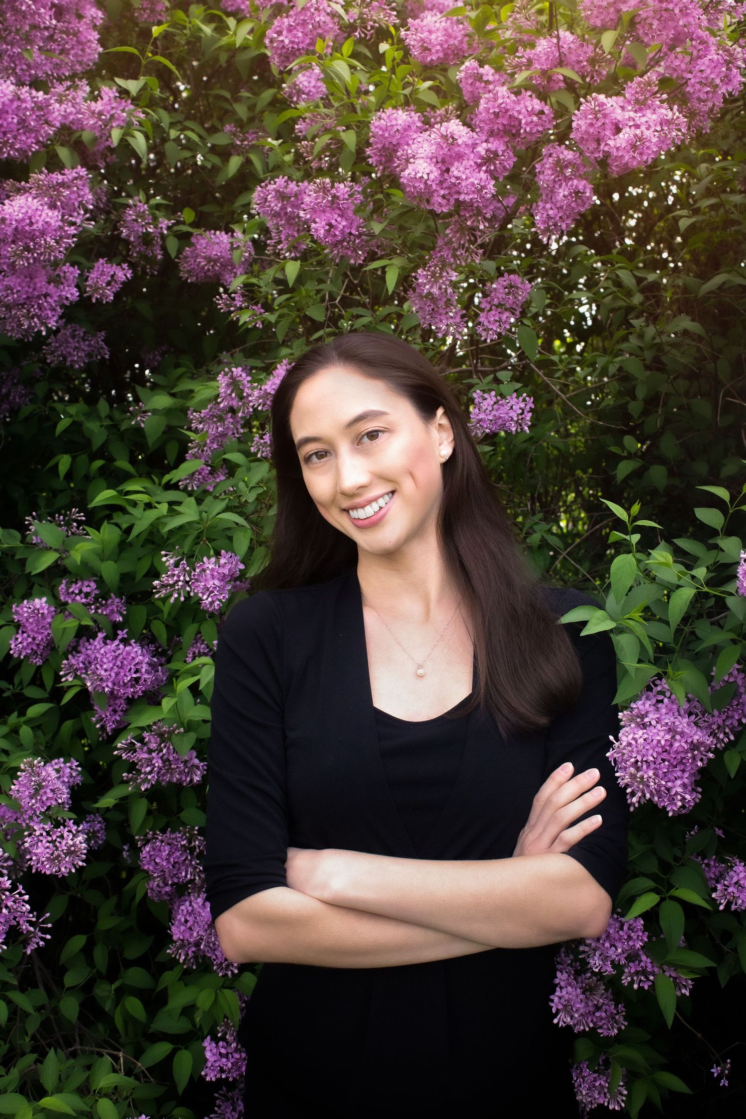 Portrait session against blooming purple lilac bushes in springtime garden setting.