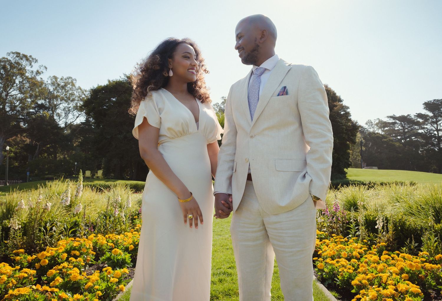 Couple sharing a tender moment in a garden with vibrant orange flowers.