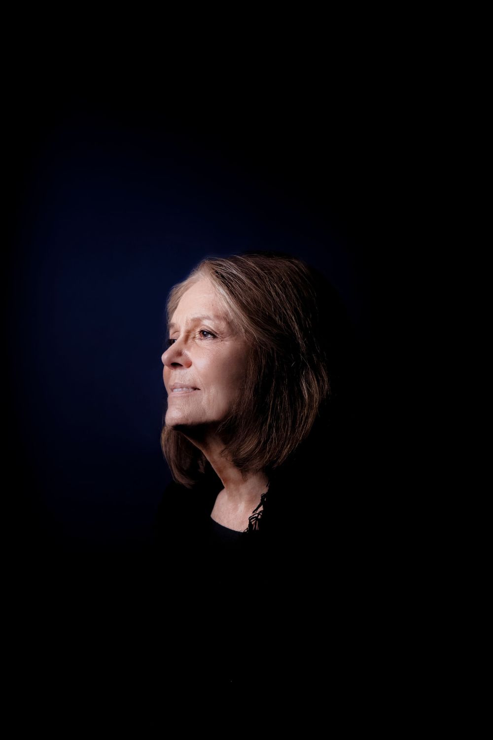 Dramatic side profile portrait with dark background and dramatic lighting.